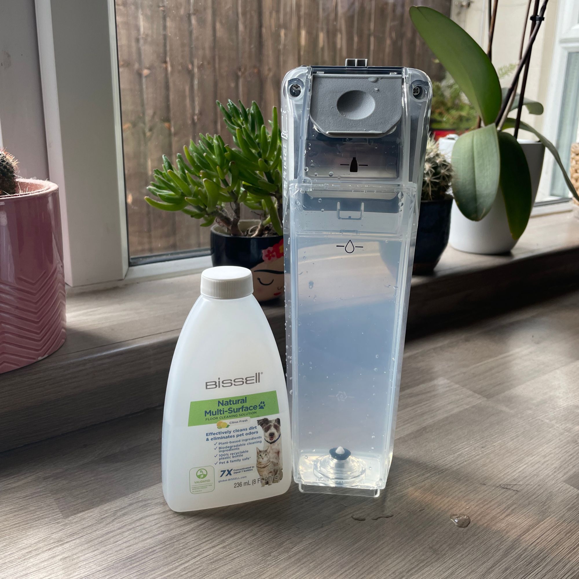 Clean water tank of Bissell Crosswave Omniforce Edge sitting next to cleaning solution