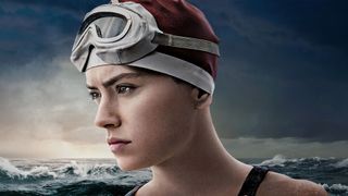 A woman wears a swimming cap and goggles in front of a choppy ocean