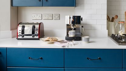 A white tiled kitchen with floral decor and a coffee machine