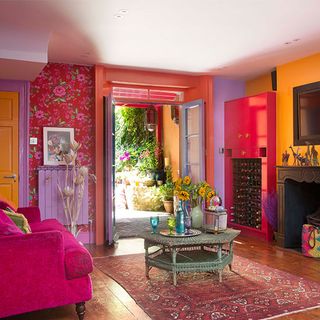 living area with pink wall and wooden floor and pink sofa