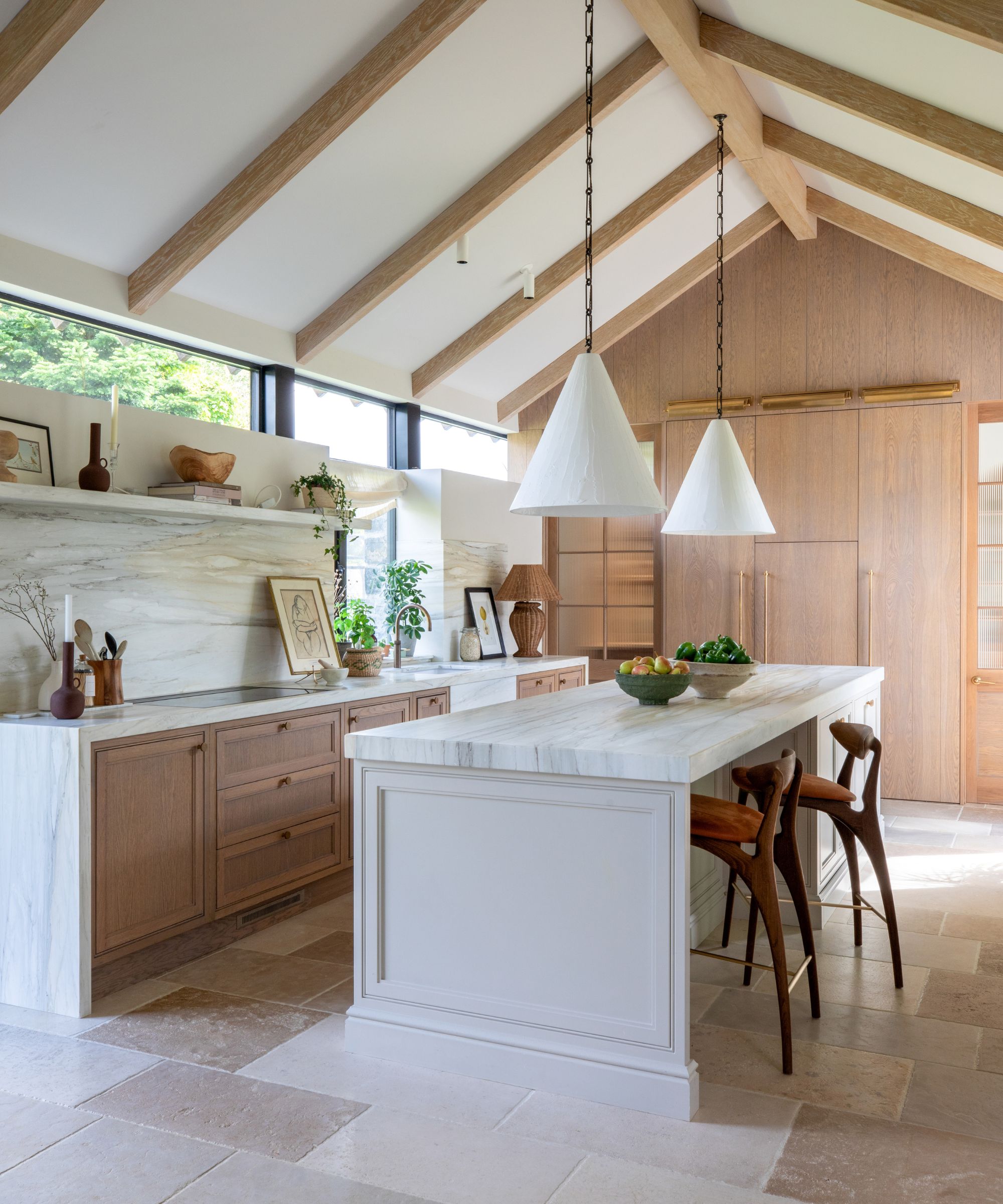 A wood and white kitchen with vaulted ceilings and marble countertops