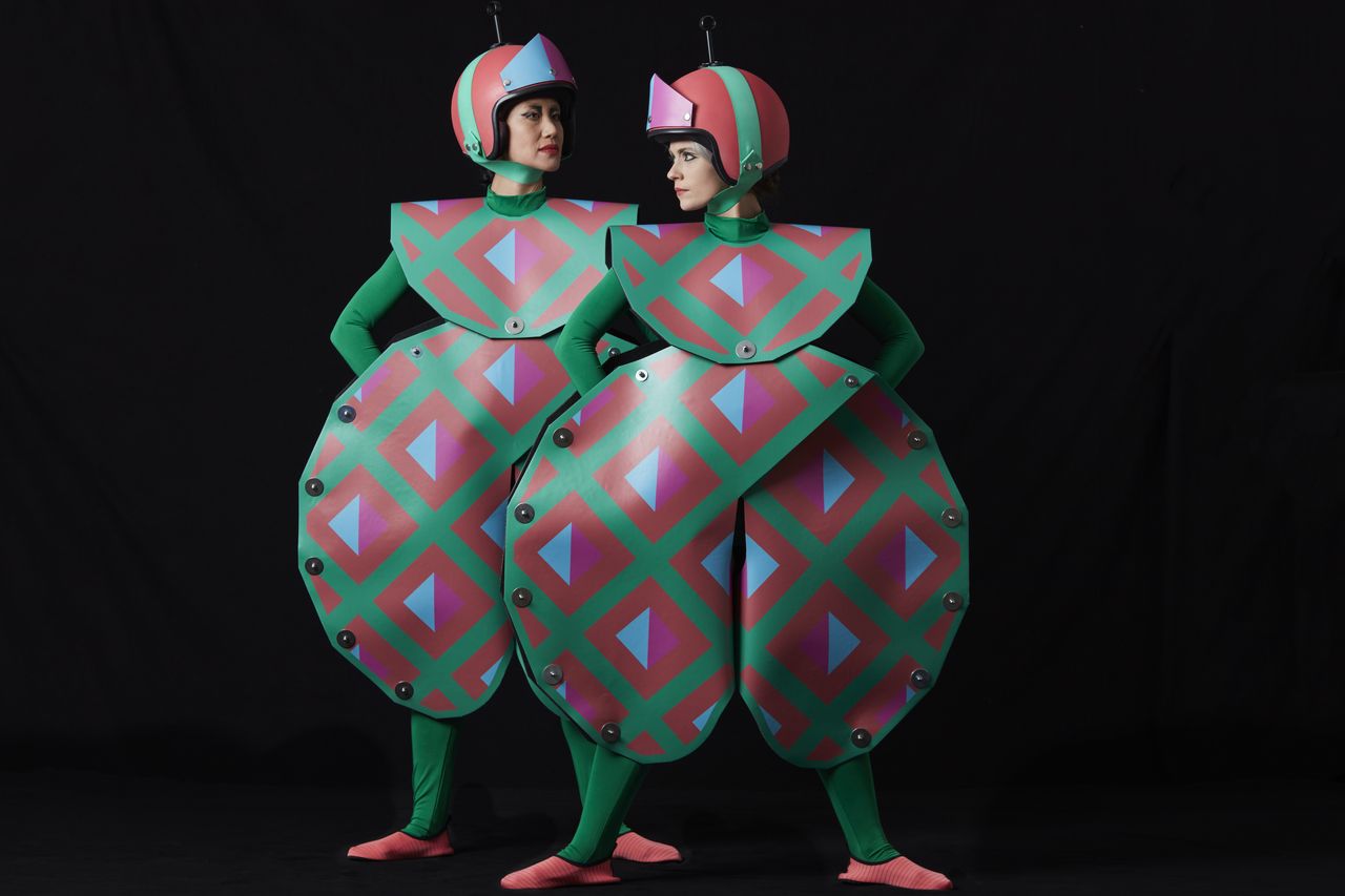 Two women wearing geometric theatrical costumes