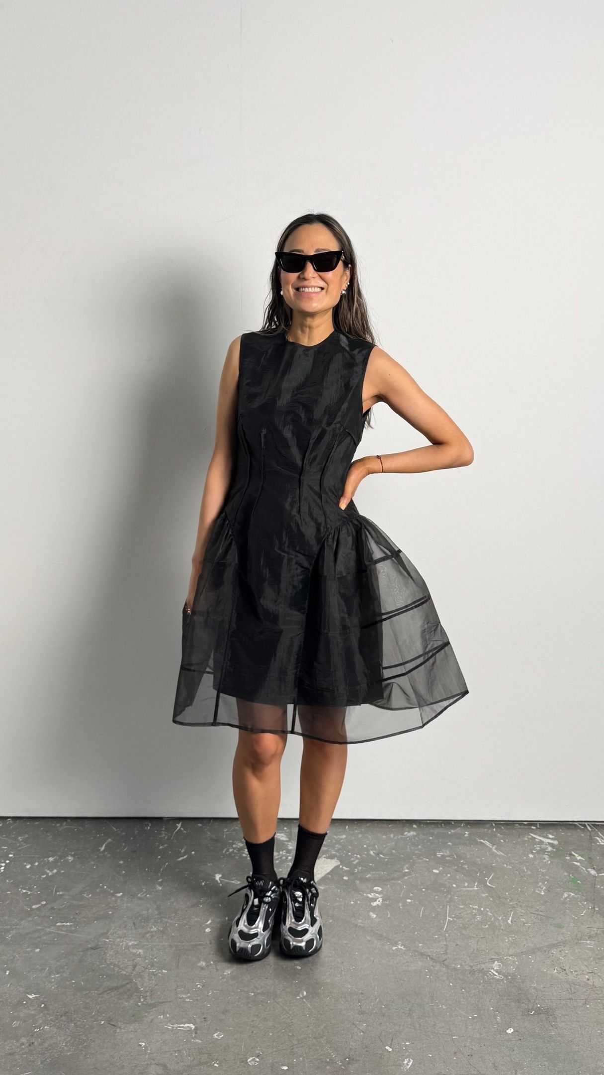 Caroline wears a black dress with black and silver sneakers.