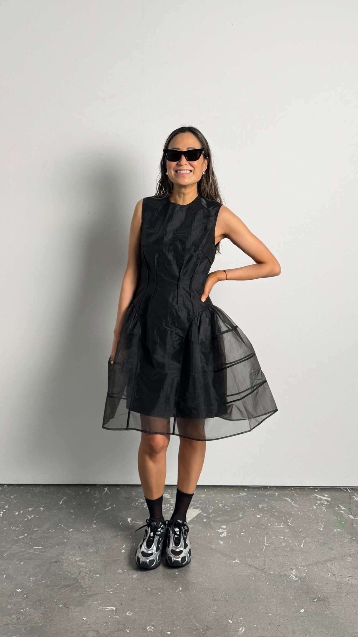 Caroline wears a black dress with black and silver sneakers.