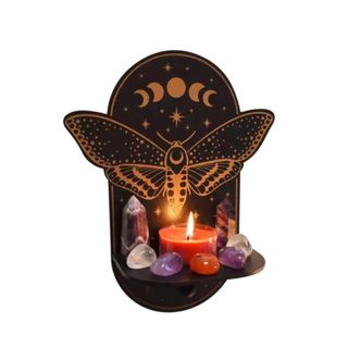 A black butterfly wall hanging with a candle and crystals around it