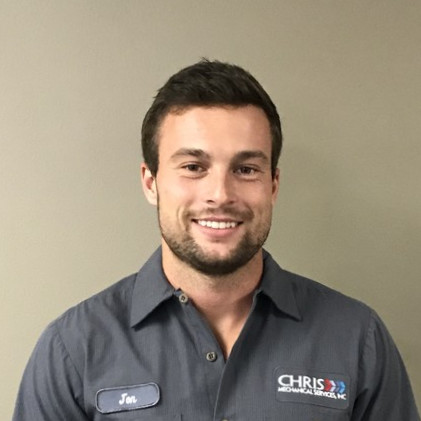 Jon is a man with brown hair and a short beard, wearing a gray collared work shirt with the company name and his name stitched on.