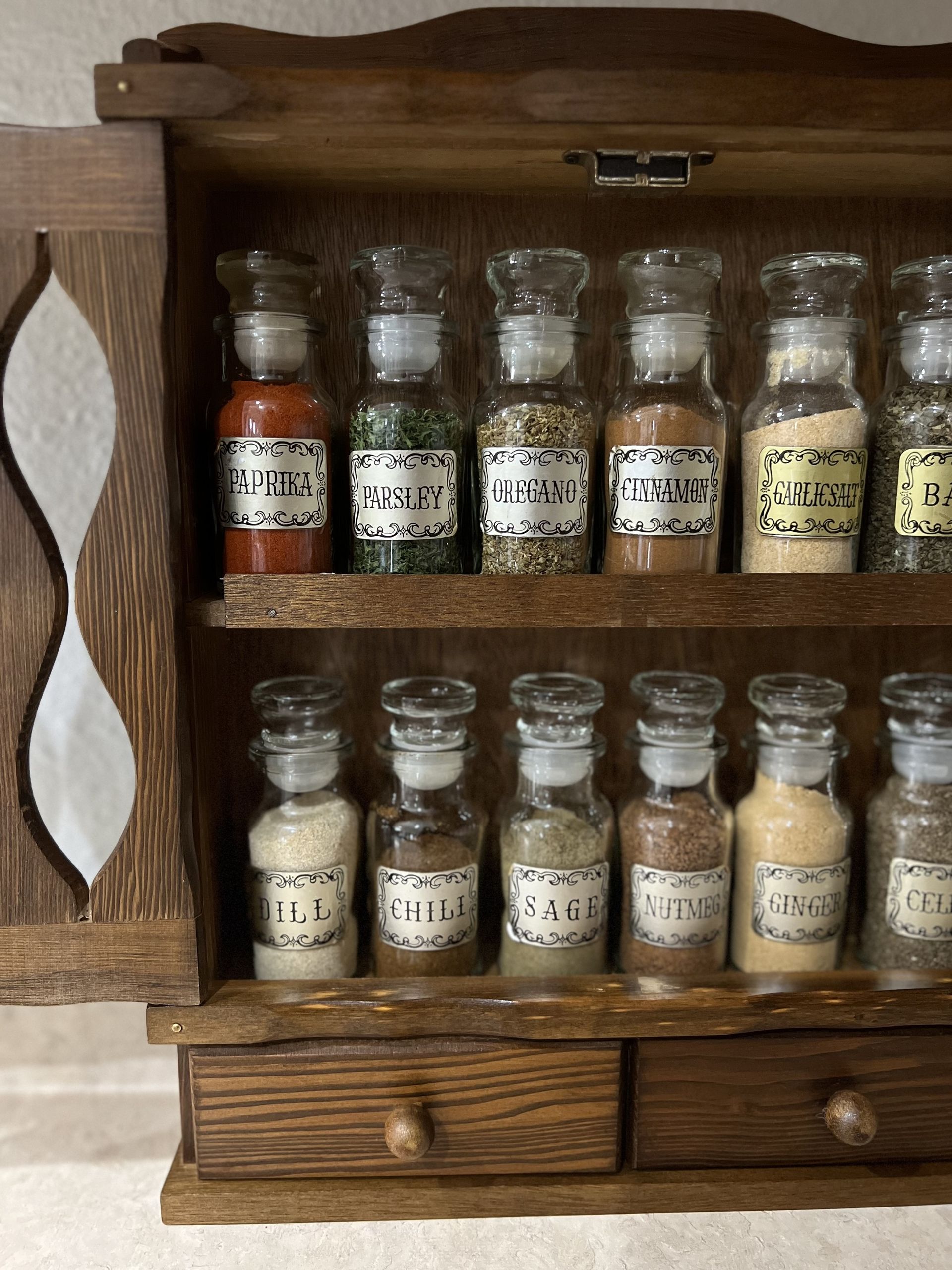 A close up of a vintage wooden spice rack with a selection of spices and herbs in jars with labels
