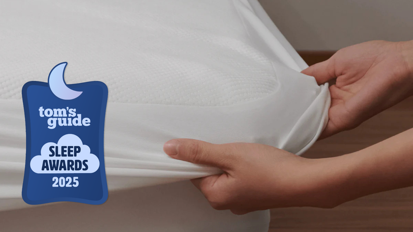 TG Sleep Awards badge on an image of a hand putting on the Coop Ultra-Tech Waterproof mattress protector on the bed