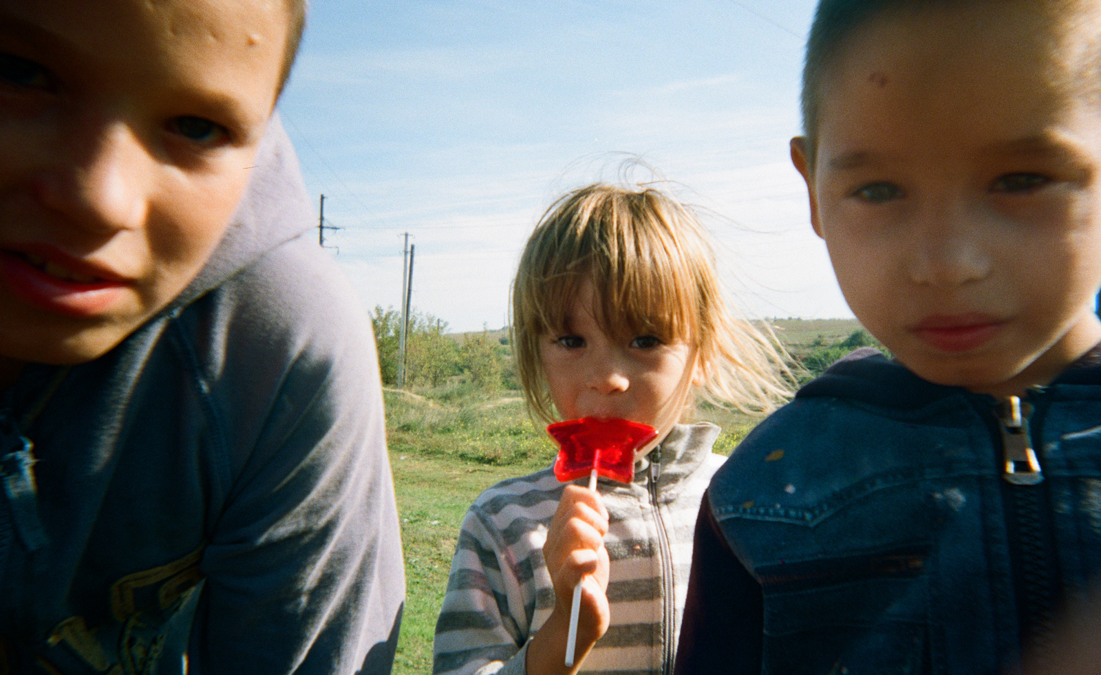 Three Ukrainian children, one eating lolly