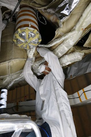 An engineer works on the Parachute Deployment Device of the Low Density Supersonic Decelerator test vehicle in this image taken at the Missile Assembly Building at the US Navy's Pacific Missile Range Facility in Kaua‘i, Hawaii. Image released May 16th, 2014.