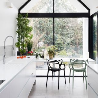 Modern conservatory kitchen extension with white units and glass doors