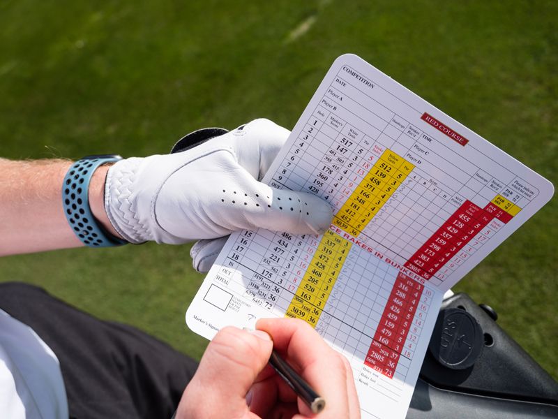 What Is A Golf Handicap? Player recording their score on a golf scorecard