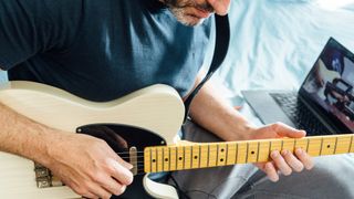 Man playing Fender Telecaster while sitting down