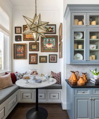 banquette seat in kitchen with blue glazed cabinet and star pendant light with art on wall