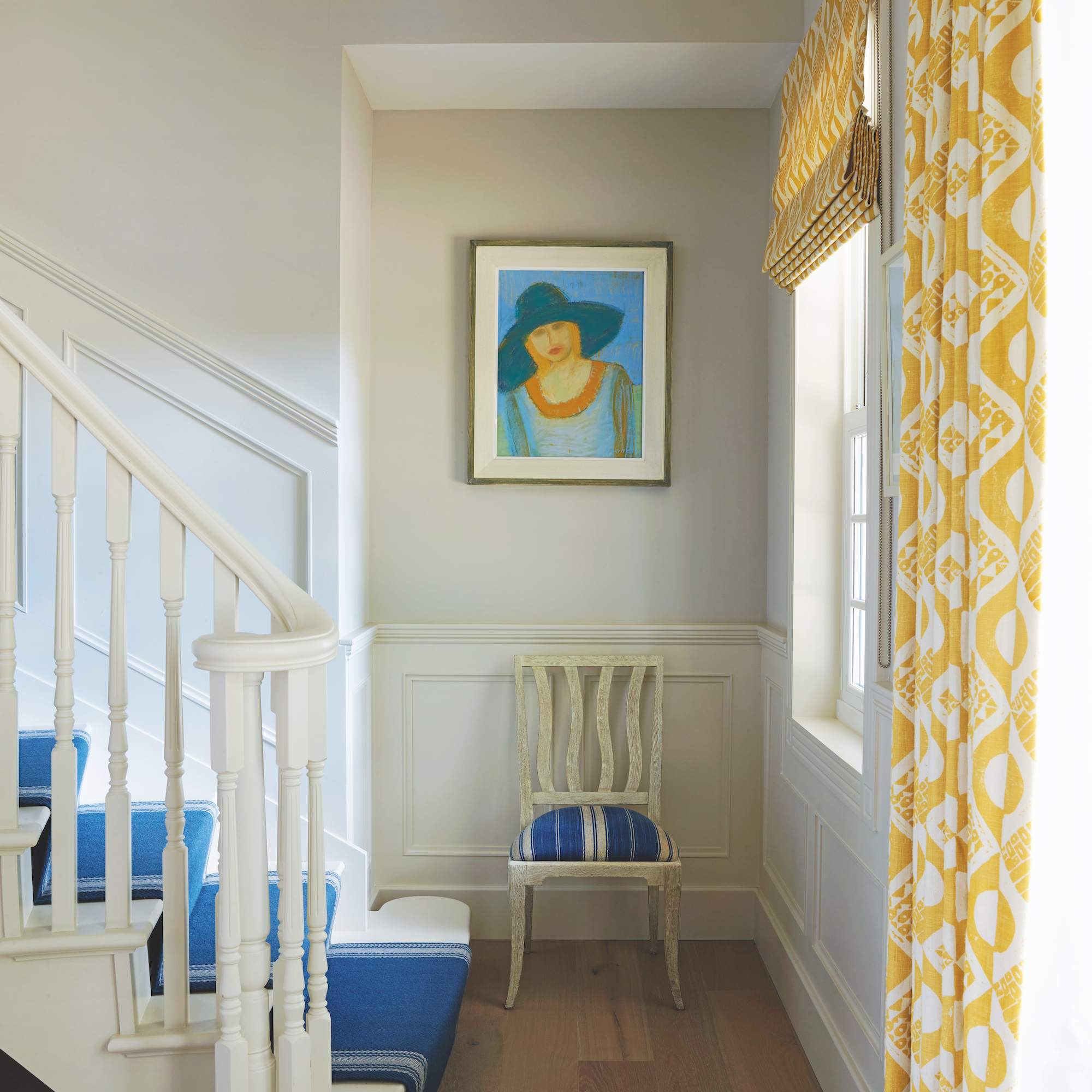 hallway with painting above a wooden dining chair and yellow curtains