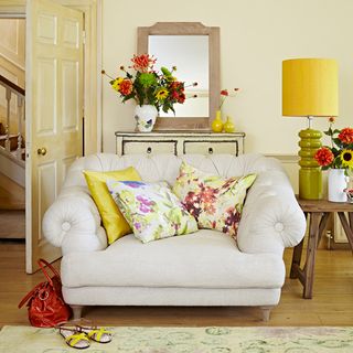 White armchair with yellow floral cushions in a neutral room