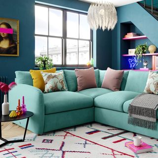 A teal coloured corner sofa in a brightly coloured living room