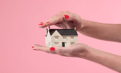 Two hands holding model house