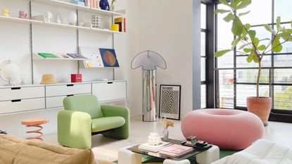 Small living room design rules are so important to follow. Here is a living room with colorful seating, white walls, wall shelving, and a window