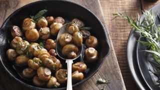 Mushrooms cooking with herbs in a pan