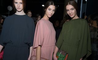 Three models in loose dresses, one black, one pink and one green