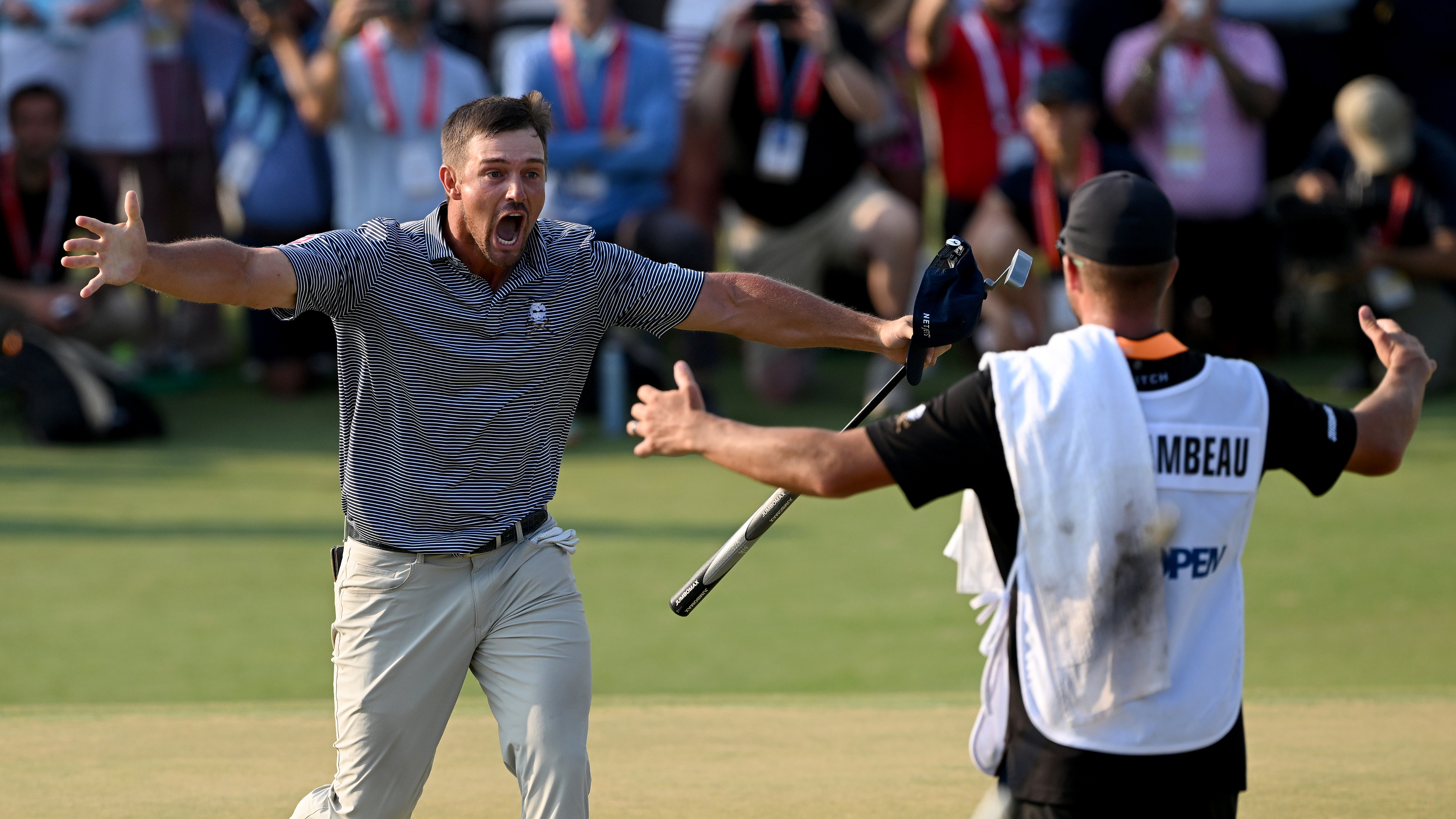 Bryson DeChambeau celebrating with his caddie on the 18th green of the 2024 US Open