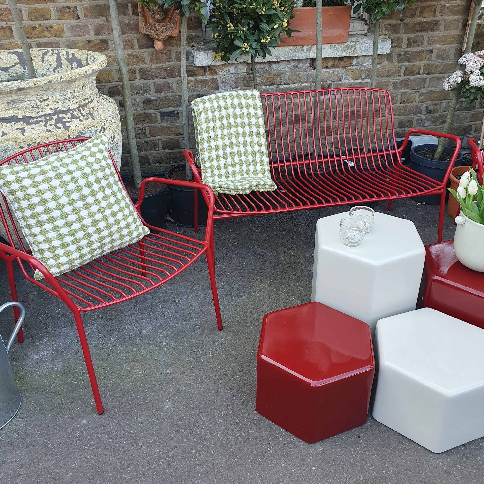 Metal garden furniture in bright red with pillar-style side tables at the Sazy press show