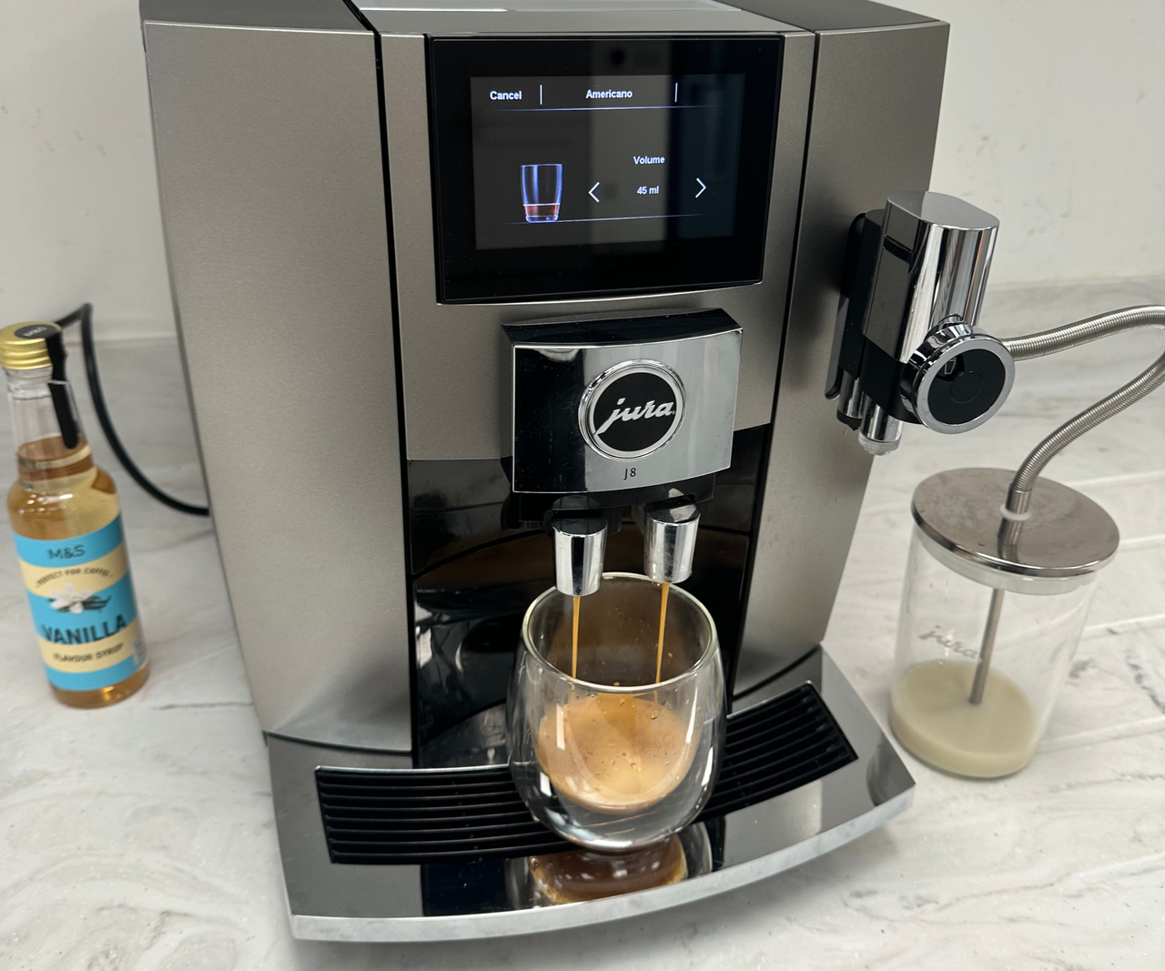 Jura J8 espresso machine pouring a shot into a glass espresso cup.