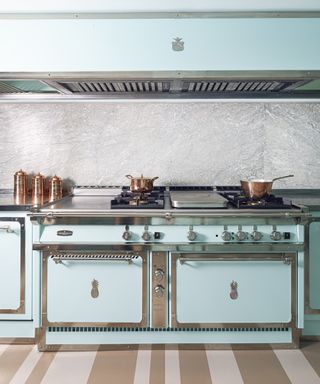 A turquoise kitchen with large turquoise range, nickel details and copper cooking pots