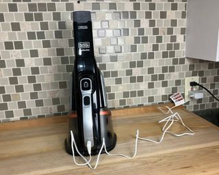 Black and Decker Dustbuster handheld vacuum cleaner plugged into power outlet in kitchen to charge