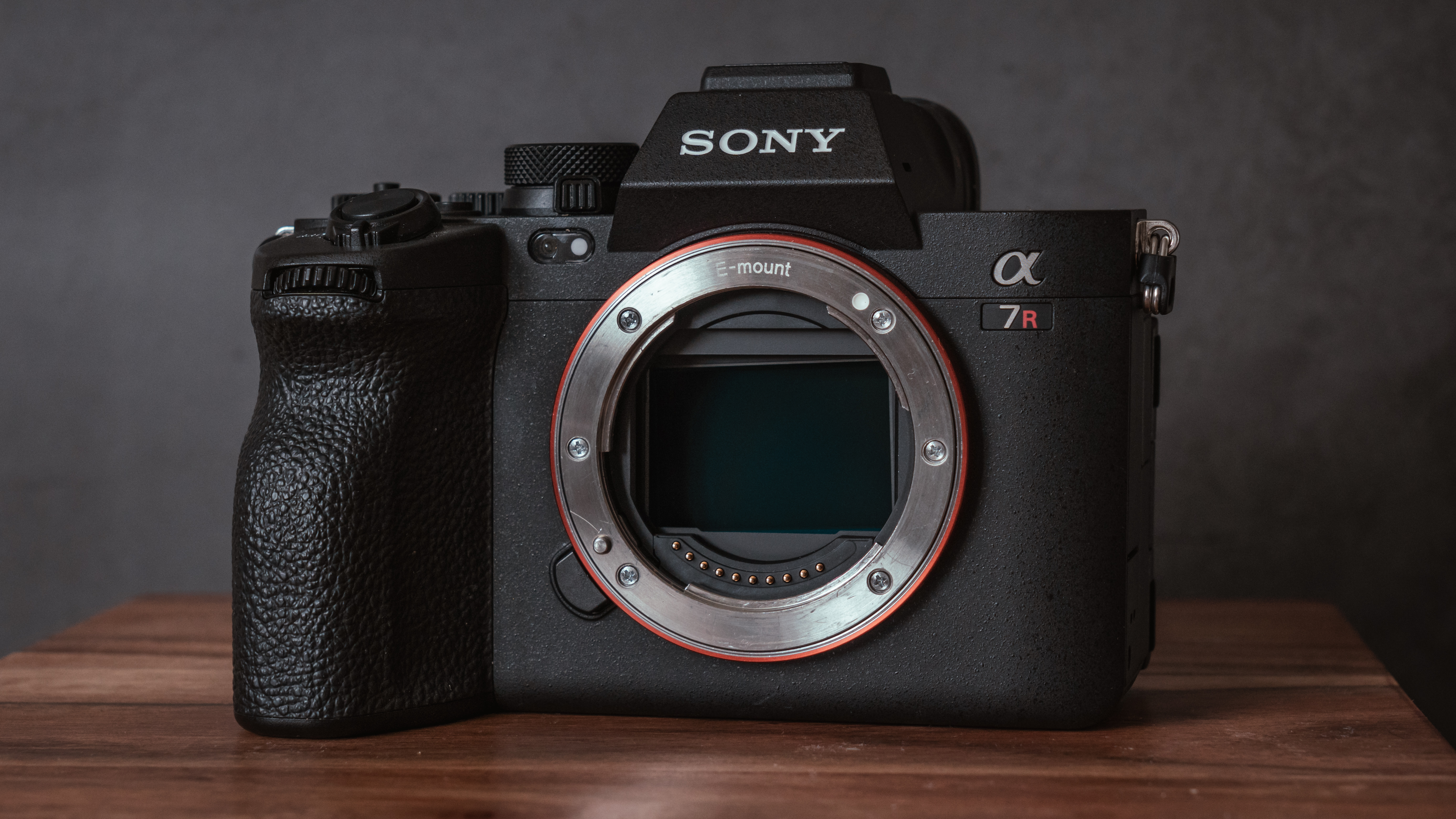 Sony A7R V camera body on a wooden surface with a gray background