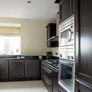 kitchen room with black cabinets and granite worktop with oven and microwave