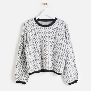 Jacquard metallic knit jumper from Oliver Bonas hanging on a wooden hanger