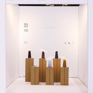 Lamps with asymmetric white shades, shown on wooden plinths at Design Shanghai 2024
