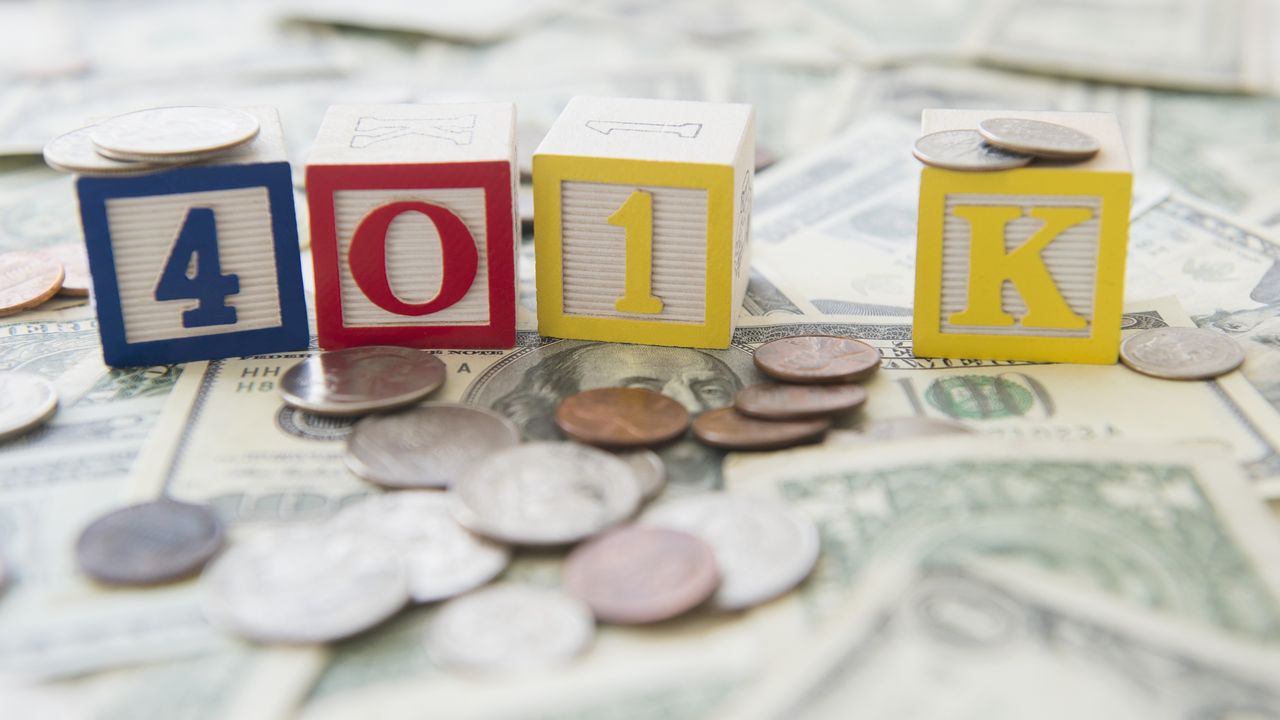 401(k) is spelled out in children&#039;s blocks sitting on top of cash and coins.