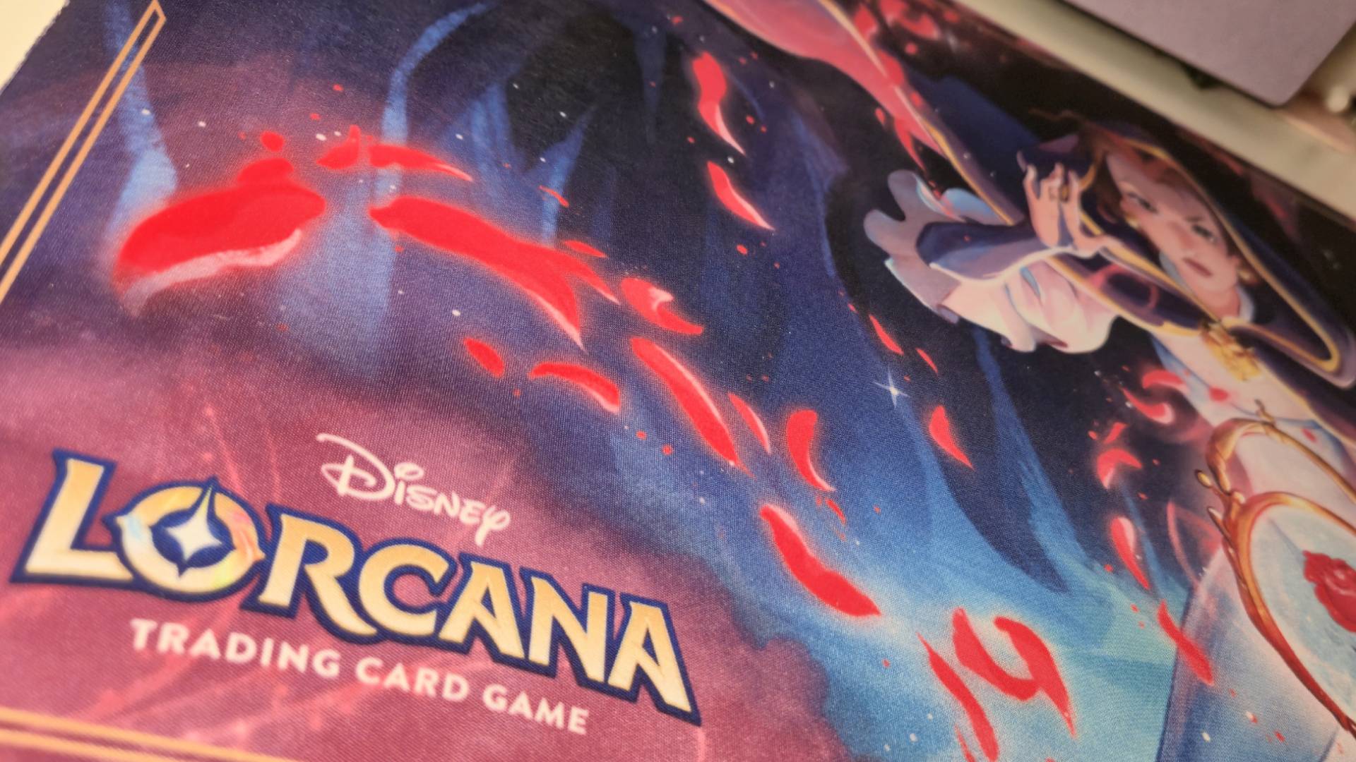 Photo of the bottom left corner of a Lorcana playmat, showing the Lorcana TCG logo.