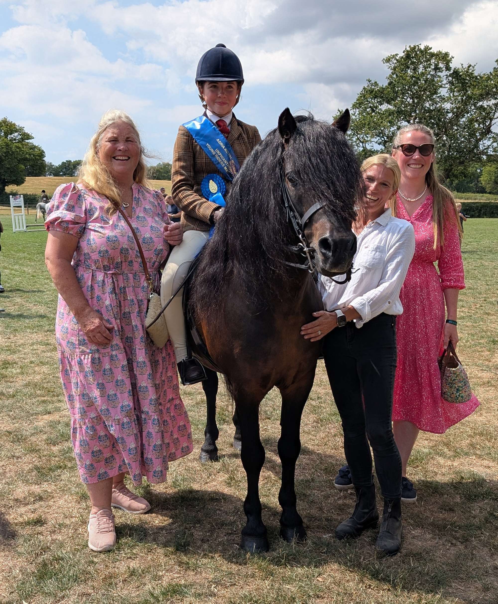 A Dartmoor pony with rider wearing a blue sash surrounded by connections