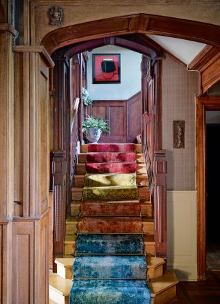 Wooden panelled staircase with colorful staircase runner