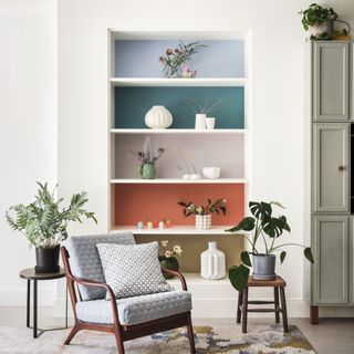 white wall with alcove with colour blocked shelves behind table and chair
