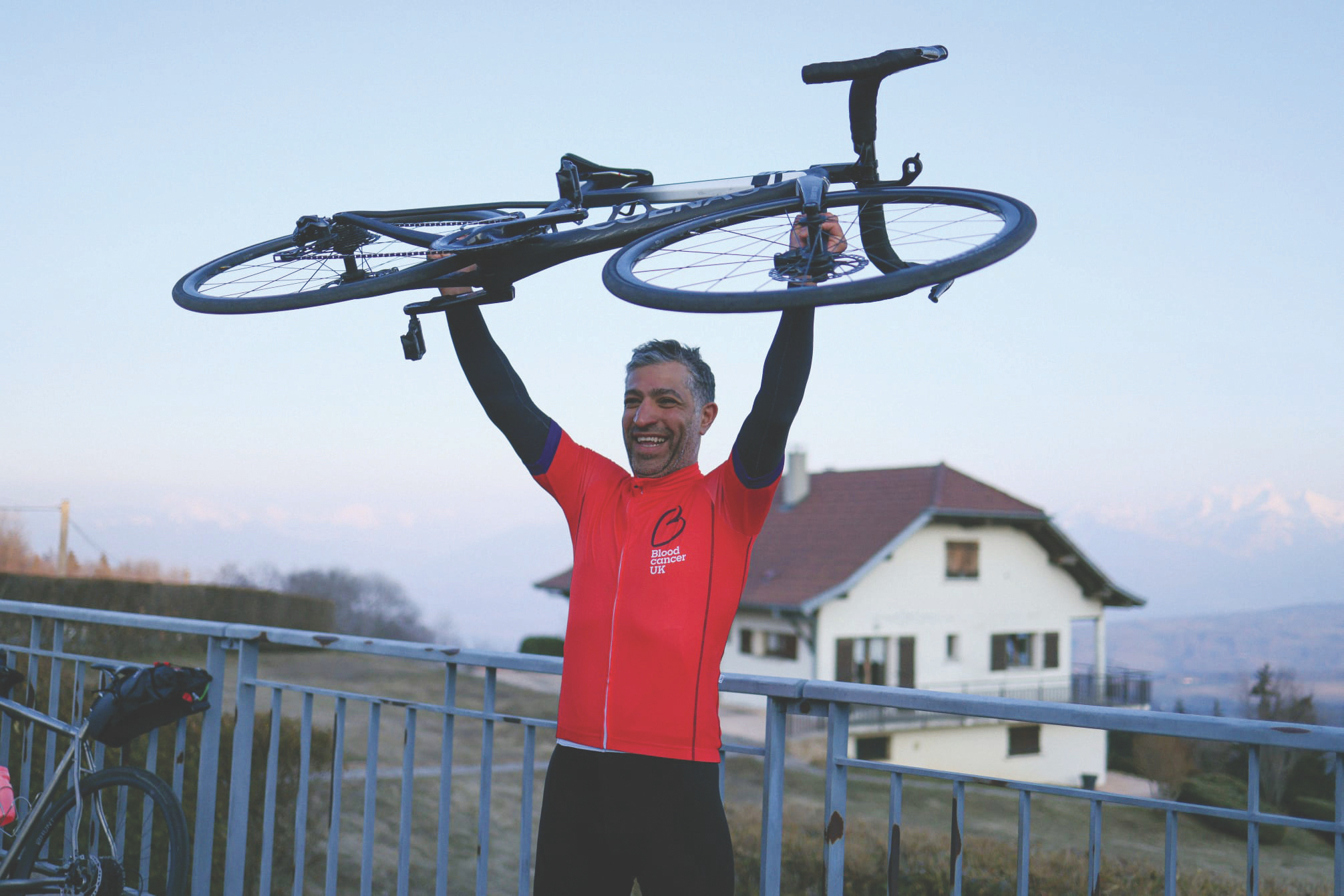Nima holds his bike aloft at the finish