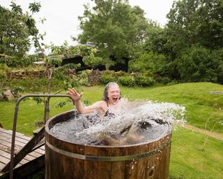 Mature woman jumping into fresh cold water tub