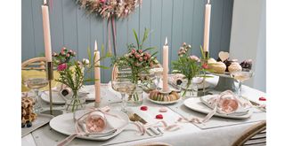 dining table set for dinner with pink ribbons and heart print tableware to show an easy Valentine's day decoration idea