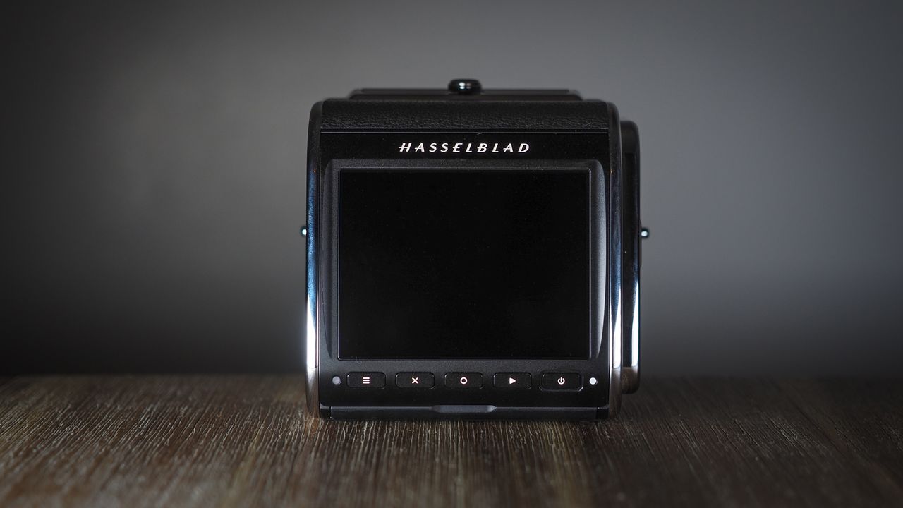 The Hasselblad 907X &amp; CFV 100C medium format camera with digital back, on a wooden table with artistic lighting