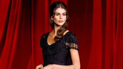 Kaia Gerber wears a black vintage Givenchy Couture gown in front of red curtains at the Academy Museum Gala on Oct. 19.