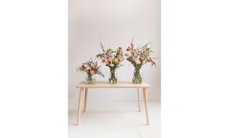 Flower bouquets in glass vase with wooden table