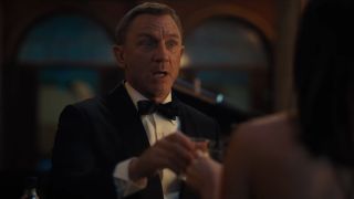 Daniel Craig toasts a quick drink with Ana de Armas in No Time To Die.