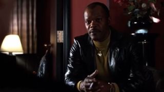 Samuel L. Jackson in a leather jacket with his fingers intertwined