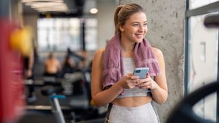 a photo of a woman in the gym with a towel around her neck