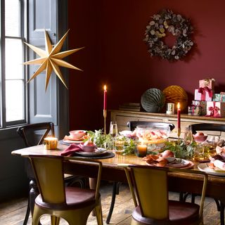 christmas flower arrangement on a red and gold themed table with a large gold star hanging off the wall and a wreath on a red wall