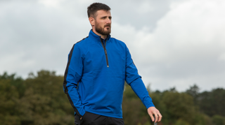 A golfer poses in the Under Armour Storm Windstrike 1/2 Zip